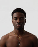 Man wearing gold necklaces on a plain background