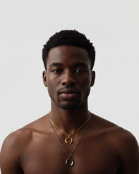 Man wearing gold necklaces on a plain background
